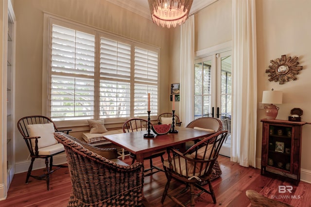 dining area with ornamental molding, an inviting chandelier, hardwood / wood-style flooring, and french doors