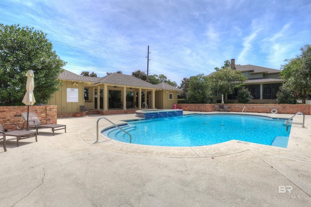 view of swimming pool featuring a hot tub and a patio area