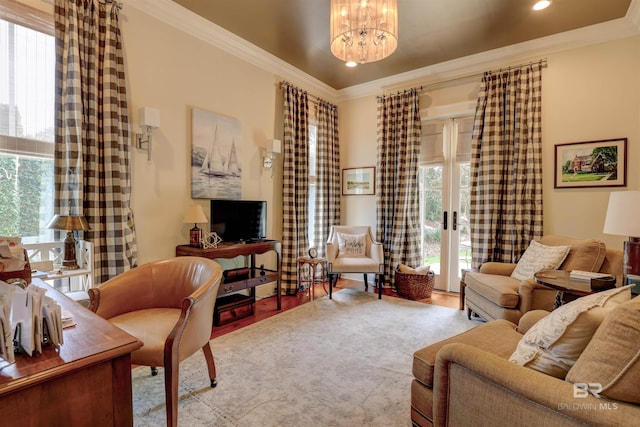 living room with light hardwood / wood-style floors, a wealth of natural light, ornamental molding, and a chandelier