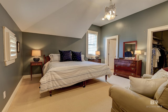 carpeted bedroom featuring a walk in closet, a closet, lofted ceiling, and a chandelier