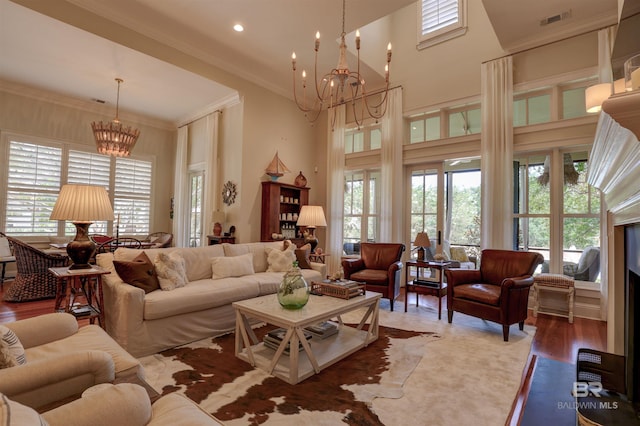 living room featuring hardwood / wood-style flooring, an inviting chandelier, and ornamental molding