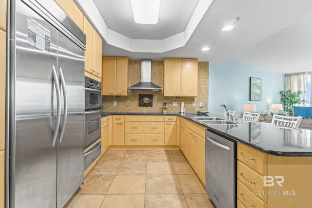 kitchen featuring wall chimney range hood, light brown cabinets, appliances with stainless steel finishes, and sink