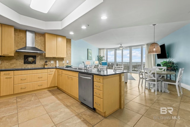 kitchen with ceiling fan, light brown cabinetry, wall chimney exhaust hood, and dishwasher