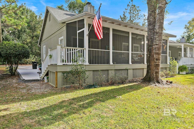 view of home's exterior featuring a sunroom and a lawn