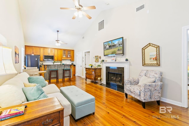 living room with hardwood / wood-style flooring, ceiling fan, and high vaulted ceiling