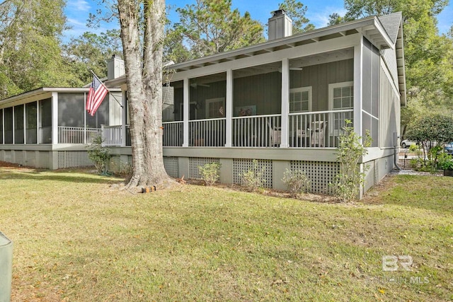 rear view of property featuring a sunroom and a yard