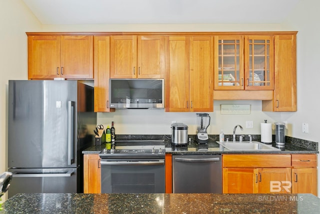 kitchen featuring dark stone countertops, appliances with stainless steel finishes, and sink