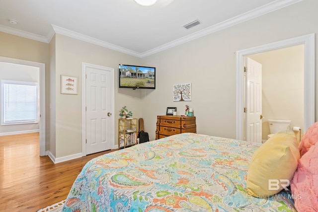 bedroom with hardwood / wood-style floors, ensuite bath, and crown molding