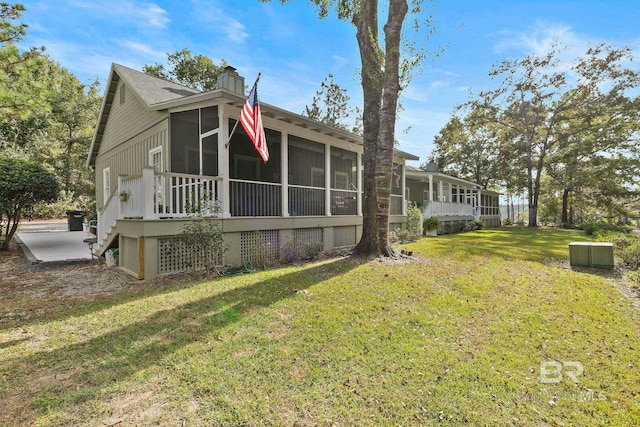 view of side of home featuring a lawn and a sunroom