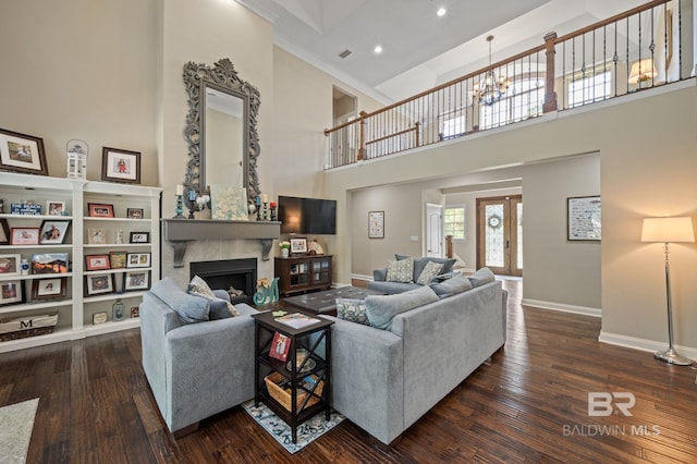 7371 Maureen Cir, Spanish Fort, AL 36527 - living room with a towering ceiling, dark wood-type flooring, a fireplace, a chandelier, and crown molding