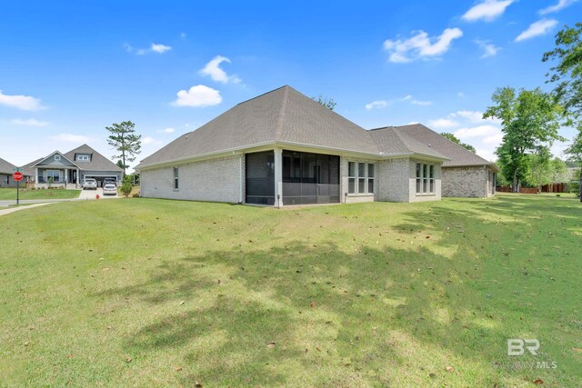 back of house with a sunroom, a lawn, and brick siding