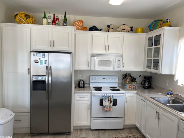 kitchen featuring white appliances, sink, light wood-type flooring, and white cabinetry