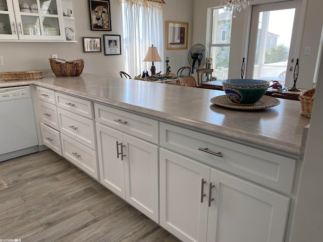 kitchen with white dishwasher, kitchen peninsula, white cabinetry, and light wood-type flooring