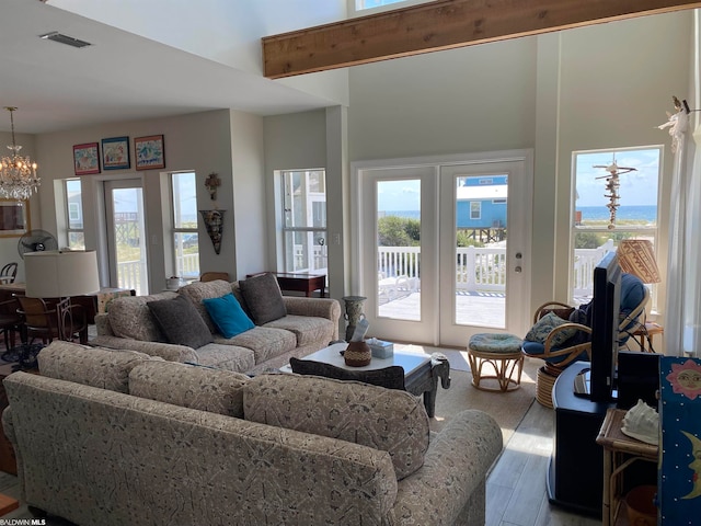 living room with a chandelier, plenty of natural light, light hardwood / wood-style flooring, and french doors
