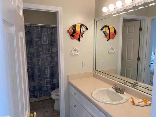 bathroom with toilet, vanity with extensive cabinet space, and wood-type flooring