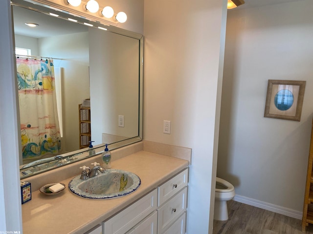 bathroom with oversized vanity, toilet, and wood-type flooring