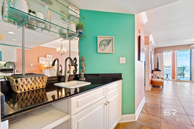 interior space featuring sink, light tile floors, a chandelier, a textured ceiling, and white cabinetry