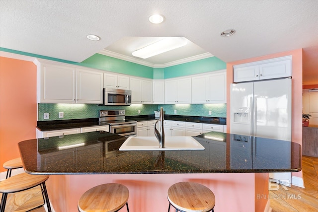 kitchen with appliances with stainless steel finishes, tasteful backsplash, a breakfast bar, and crown molding