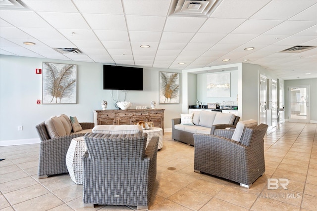 living room with light tile floors, a drop ceiling, and french doors