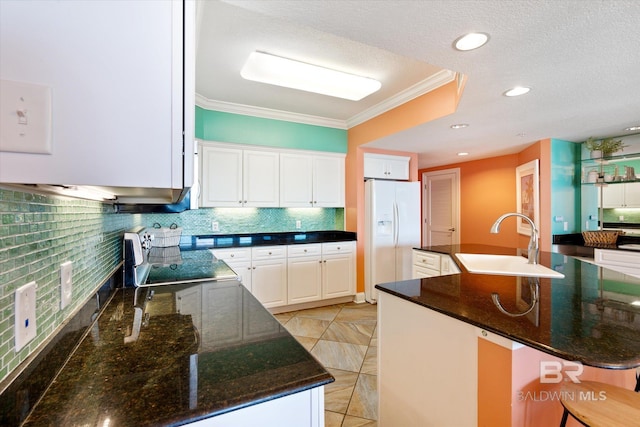 kitchen featuring white fridge with ice dispenser, a kitchen island with sink, range with electric cooktop, and dark stone counters