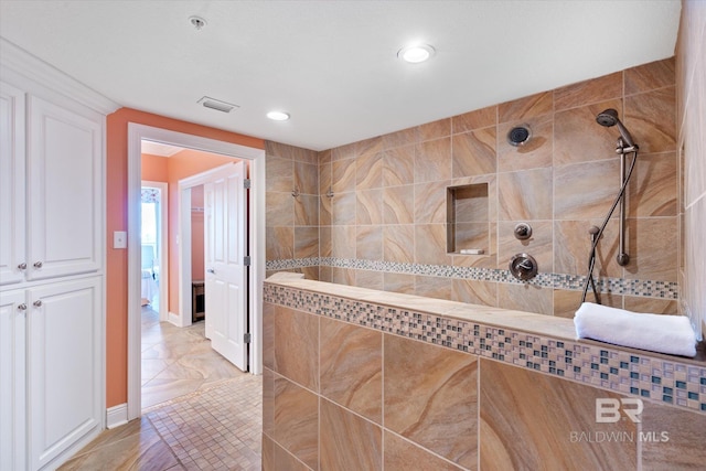 bathroom featuring tile flooring and tiled shower