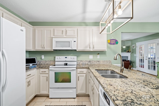 kitchen featuring white appliances, light tile patterned floors, white cabinets, french doors, and a sink