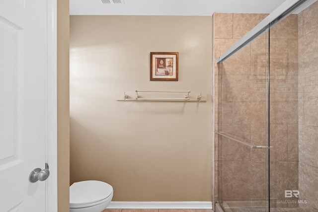 bathroom with a stall shower, baseboards, visible vents, and toilet