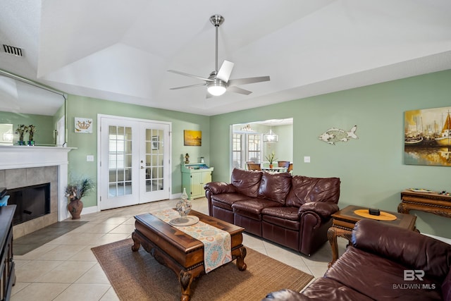 living area featuring light tile patterned floors, a tile fireplace, visible vents, french doors, and a tray ceiling