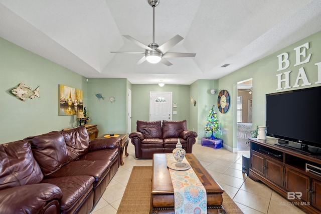 living room featuring a ceiling fan, a raised ceiling, visible vents, and light tile patterned floors