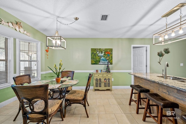 dining area with a textured ceiling, light tile patterned flooring, visible vents, and baseboards