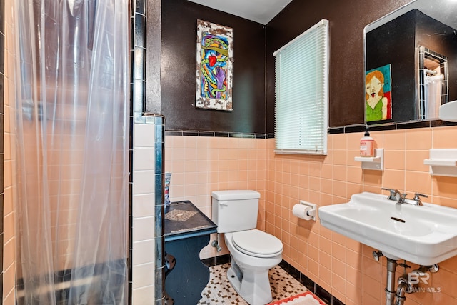 bathroom with tile patterned floors, a wainscoted wall, toilet, curtained shower, and tile walls