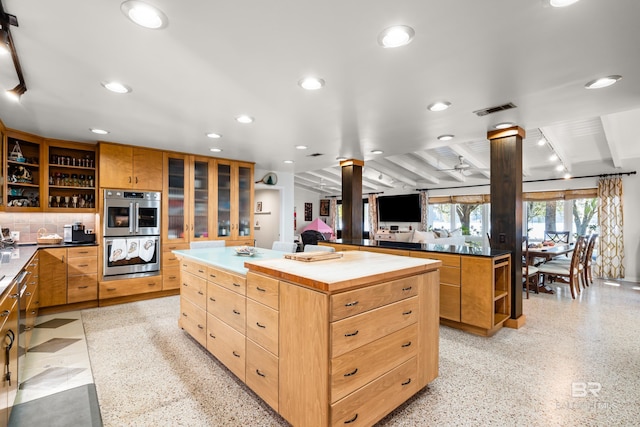 kitchen featuring visible vents, open shelves, a center island, stainless steel double oven, and ornate columns