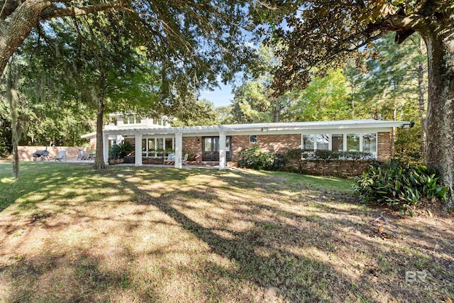 view of front facade with a front yard, brick siding, and a pergola