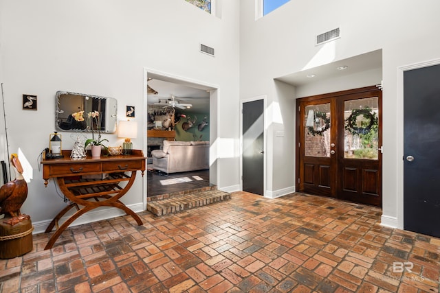 entryway featuring visible vents, a fireplace, baseboards, and french doors