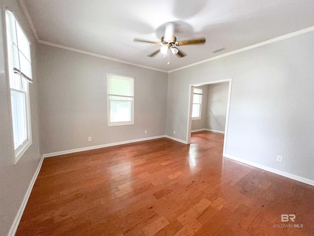 unfurnished room with baseboards, wood finished floors, visible vents, and crown molding