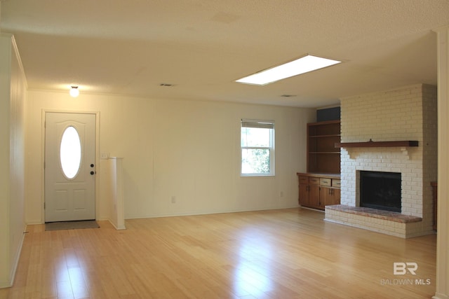 entrance foyer with light hardwood / wood-style floors, a textured ceiling, and a brick fireplace