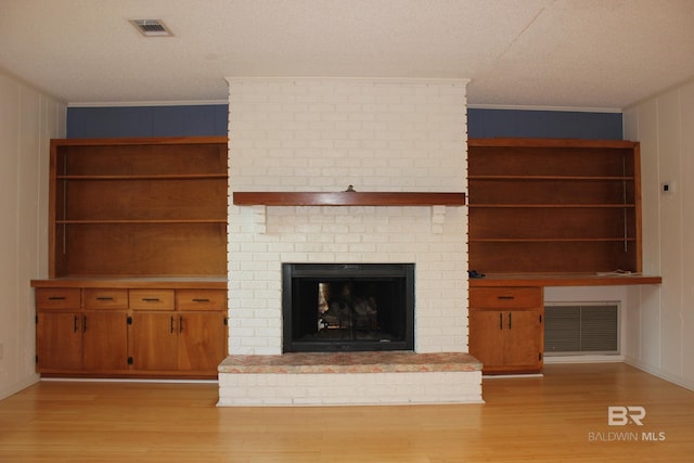 unfurnished living room featuring light wood-type flooring, a brick fireplace, and ornamental molding