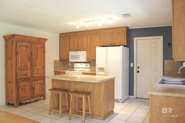 kitchen with sink, a center island, a textured ceiling, white appliances, and a breakfast bar area