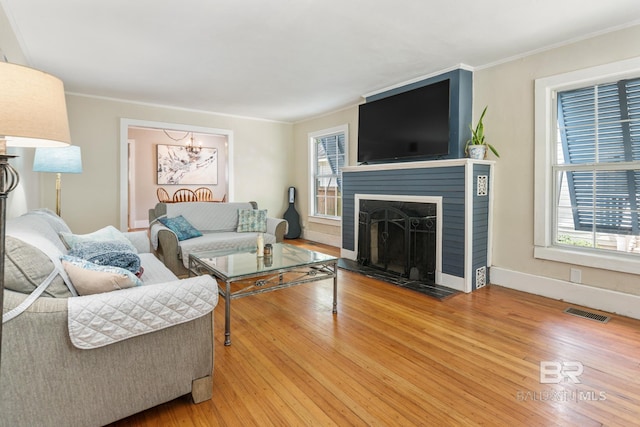 living room featuring hardwood / wood-style floors, crown molding, and a fireplace