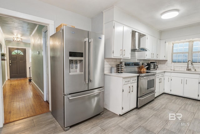 kitchen with white cabinetry, sink, wall chimney exhaust hood, and appliances with stainless steel finishes