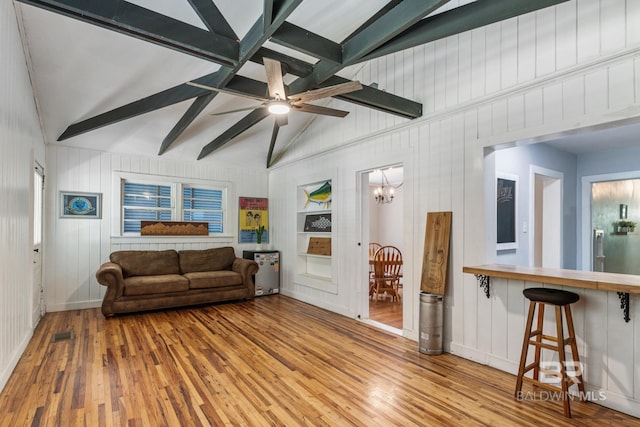 living room with lofted ceiling with beams, ceiling fan with notable chandelier, and light wood-type flooring