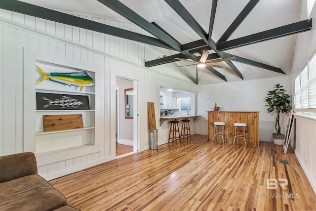 living room with vaulted ceiling with beams, light hardwood / wood-style floors, built in features, and ceiling fan