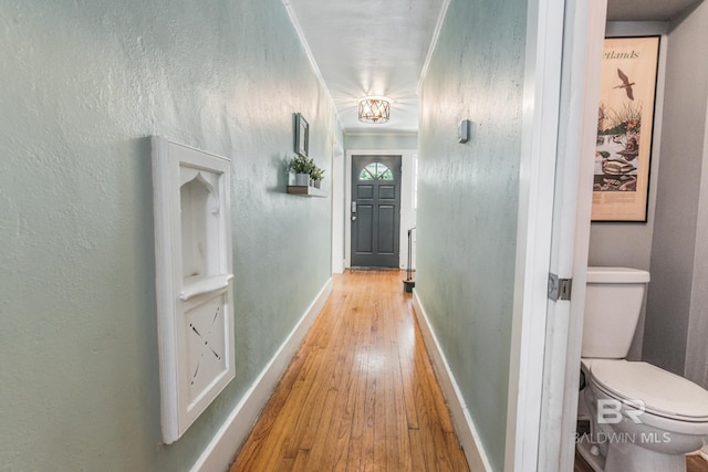 hall featuring hardwood / wood-style flooring, ornamental molding, and an inviting chandelier