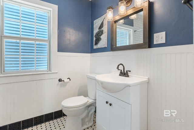 bathroom with toilet, vanity, tile patterned floors, and a wealth of natural light