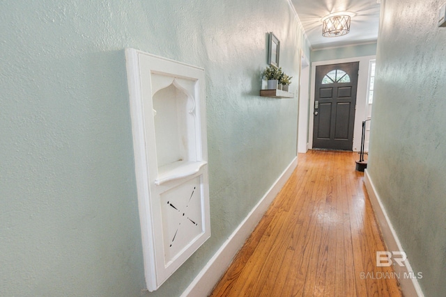 doorway to outside featuring a chandelier, crown molding, and light hardwood / wood-style floors