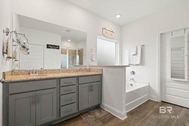 3973 Mercury Cir, Gulf Shores, AL 36542 - full bathroom featuring wood finished floors, a stall shower, double vanity, a garden tub, and recessed lighting