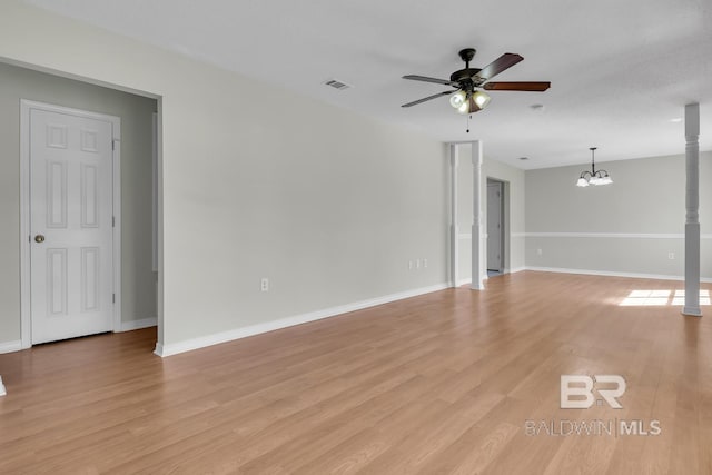 unfurnished living room featuring ceiling fan with notable chandelier, visible vents, light wood-style floors, and baseboards