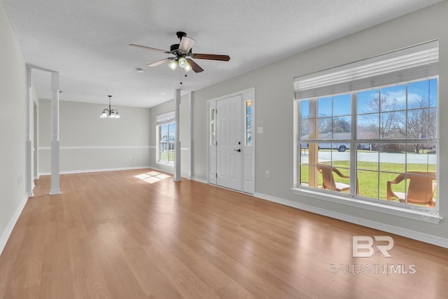 foyer featuring baseboards, light wood finished floors, and a textured ceiling