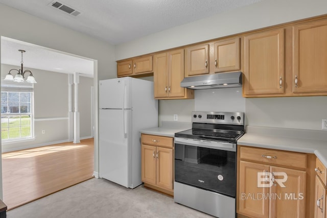 kitchen featuring visible vents, under cabinet range hood, freestanding refrigerator, stainless steel range with electric cooktop, and light countertops