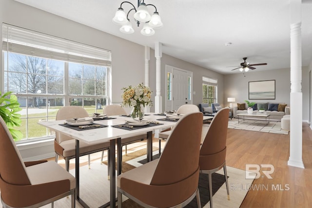 dining area with a wealth of natural light, decorative columns, and light wood finished floors